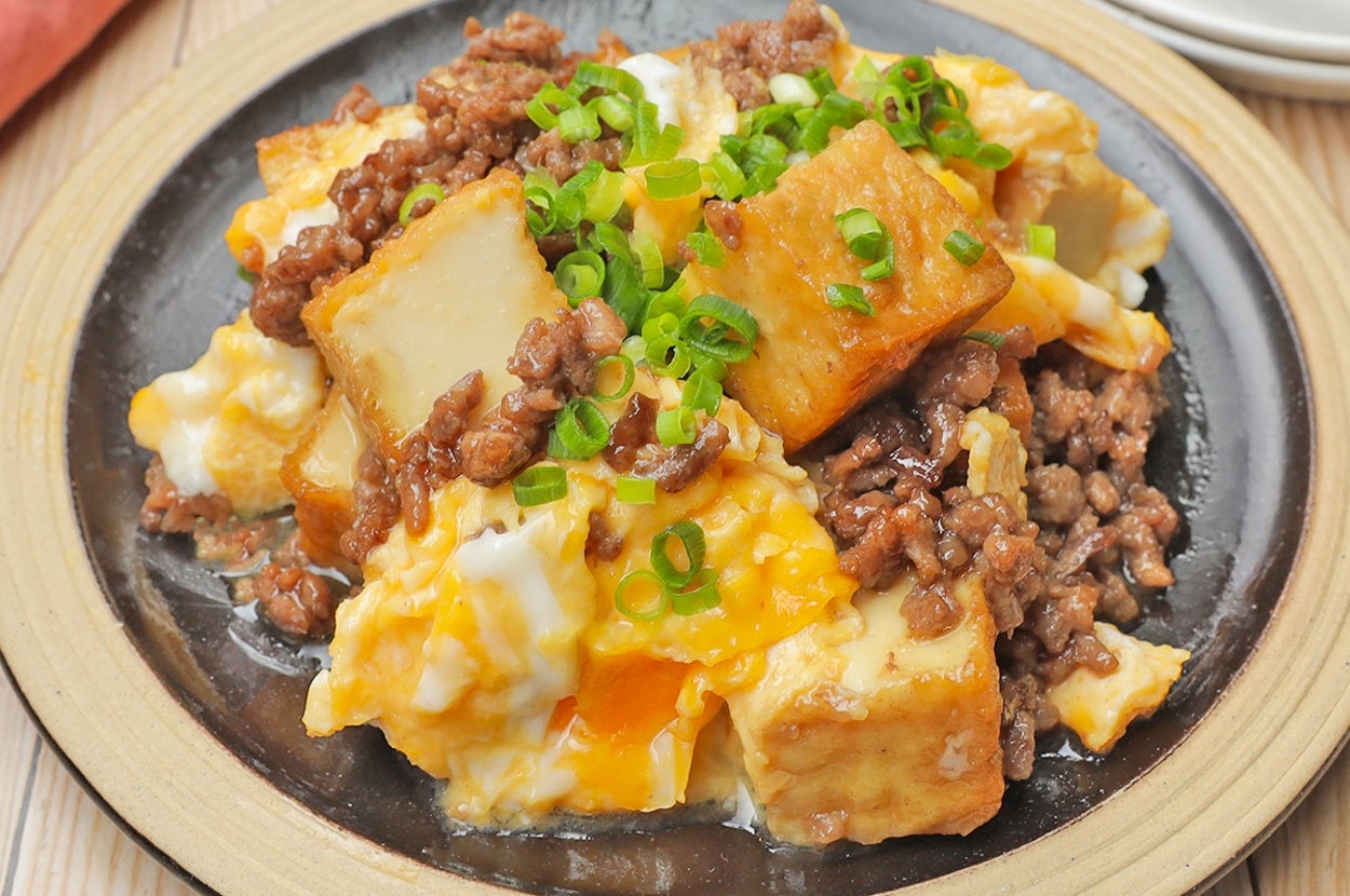 豆腐とひき肉、ネギと卵の料理が黒い皿に盛られています。