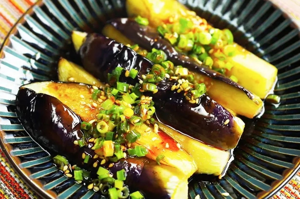 皿に盛られた焼きなすに刻みねぎとごまが振りかけられている料理。
