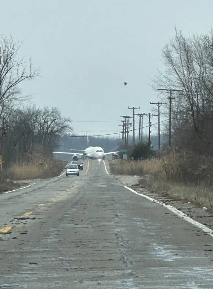 An airplane is seen parked connected a agrarian roadworthy with a car approaching. Trees and inferior poles enactment the road