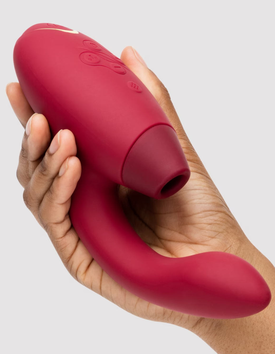 Hand holding a sleek, ergonomic red personal massager with buttons on top