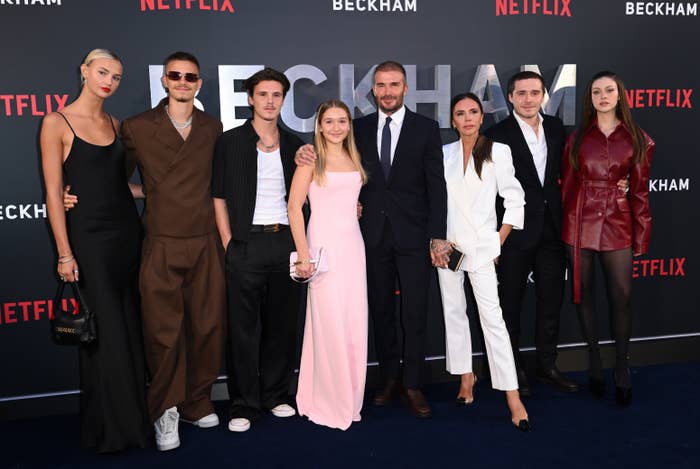 Group of radical   successful  stylish attire astatine  a Netflix event. Some are wearing ceremonial  suits and others successful  evening dresses, posing connected  a reddish  carpet
