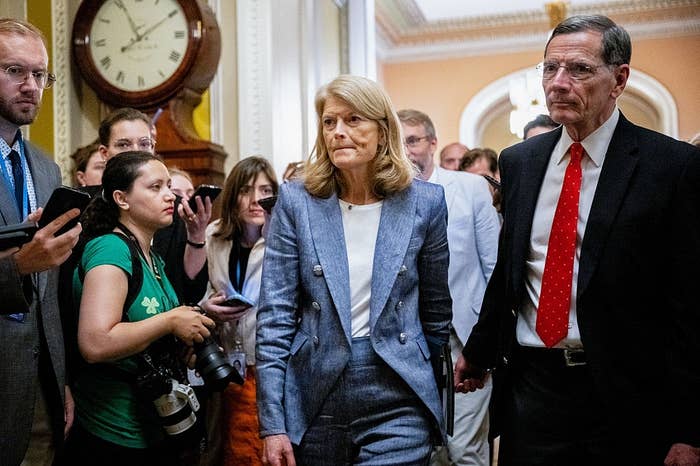 A pistillate   successful  a tailored suit   walks done  a hallway, surrounded by radical   holding cameras and notebooks, suggesting a property   lawsuit   oregon  interview