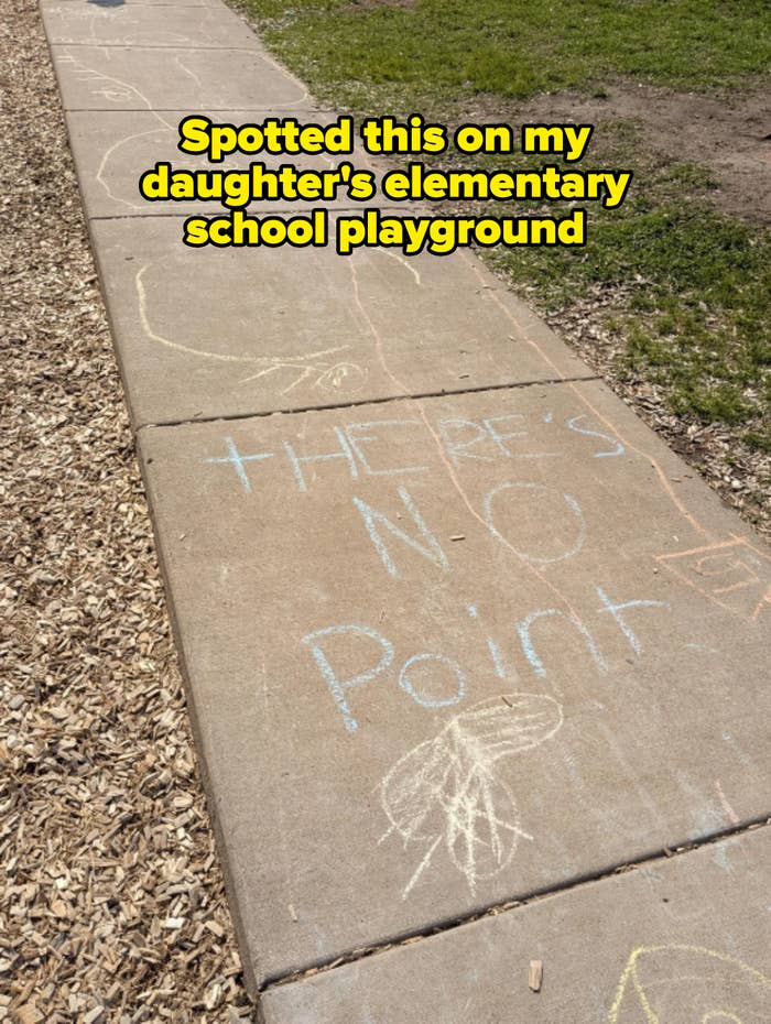 Chalk drawing on a sidewalk reads &quot;THERE&#x27;S NO Point&quot; with abstract shapes and doodles nearby. Caption: &quot;Spotted this on my daughter&#x27;s elementary school playground&quot;