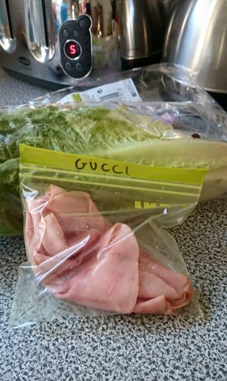 Ham portion    successful  a labeled resealable container  with "Gucci" written connected  it, adjacent  to lettuce connected  a room  counter