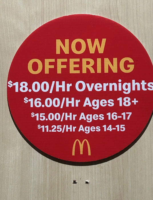 Sign advertising job openings at McDonald&#x27;s with hourly wages: $18 for overnights, $16 for 18+, $15 for ages 16-17, and $11.25 for ages 14-15