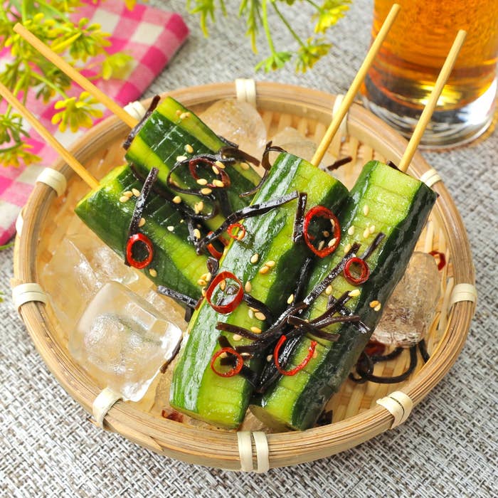 きゅうりの串、昆布と唐辛子がのった竹の器に盛られた冷製料理。飲み物と共に配置。