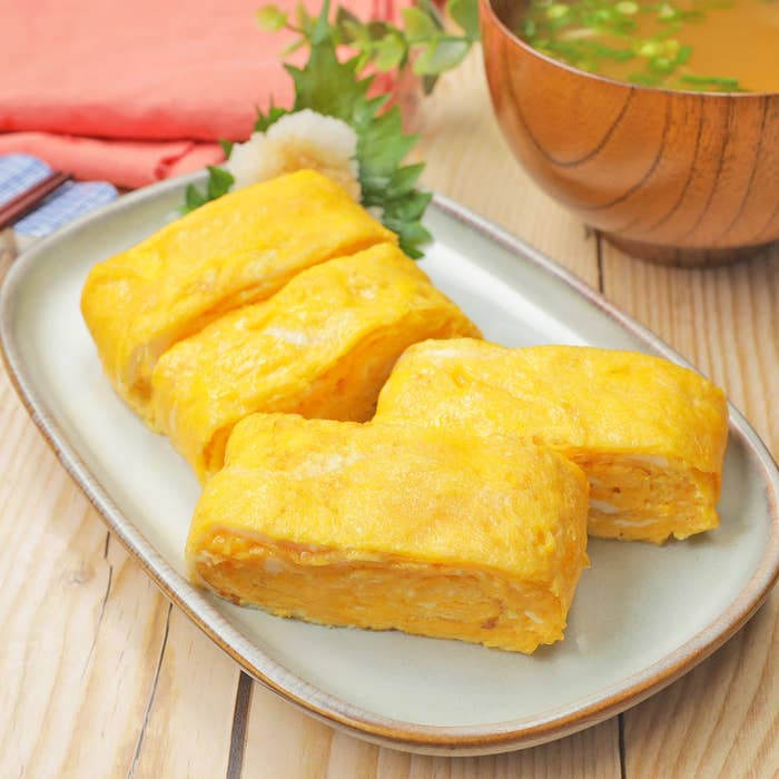 卵焼きのスライスが皿に乗っており、横にみそ汁が添えられている。朝食セットとして提供されている。