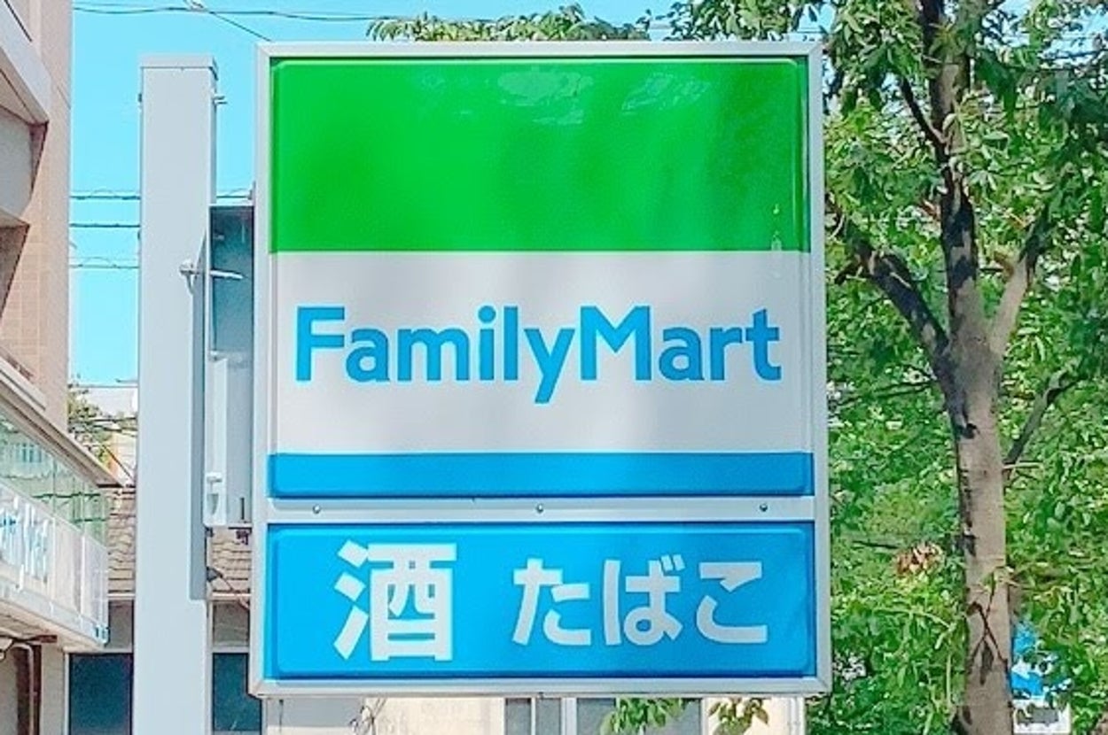 日本のファミリーマート店舗の看板。「酒」「たばこ」の表示あり。街中の風景。