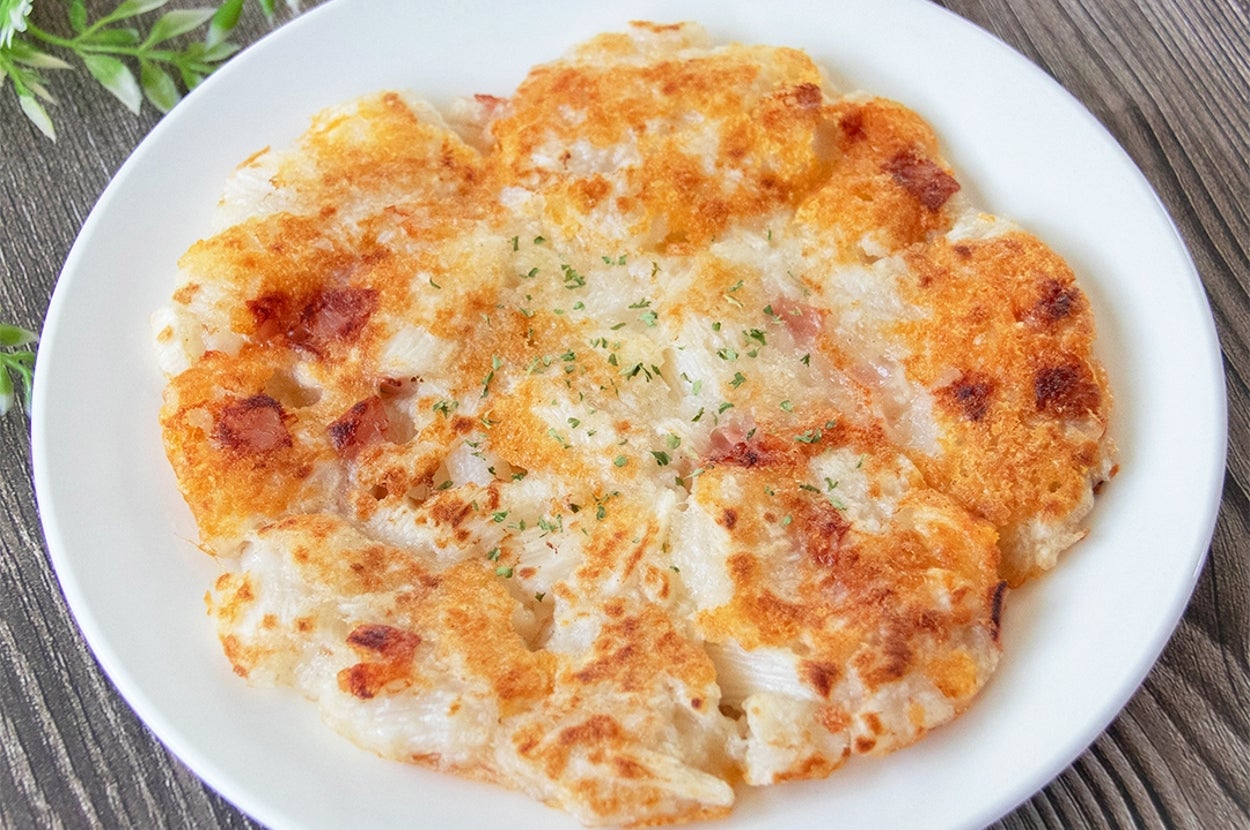 白い皿に盛られた長芋とベーコンのチーズ焼き。上に乾燥パセリがかかっている。