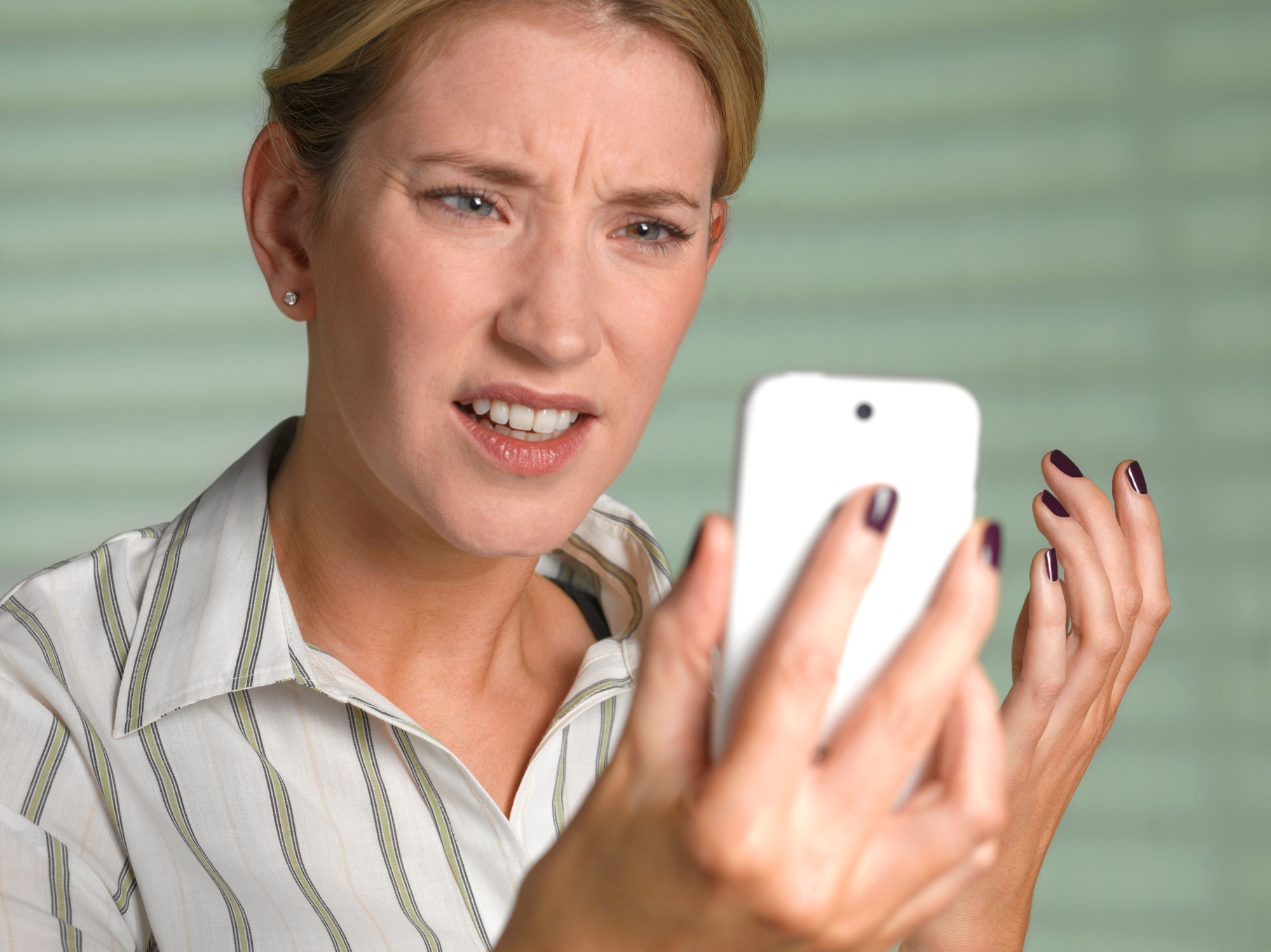 Person i en stripet skjorte ser forvirret ut mens han holder en smarttelefon