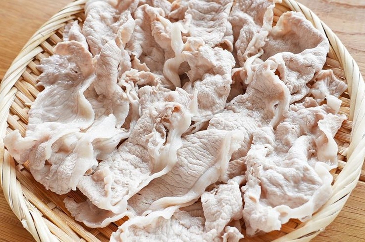 竹のざるに盛られた薄切りのゆで豚肉。