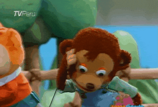 A puppet monkey in overalls appears to speak animatedly with another puppet on a TV show scene