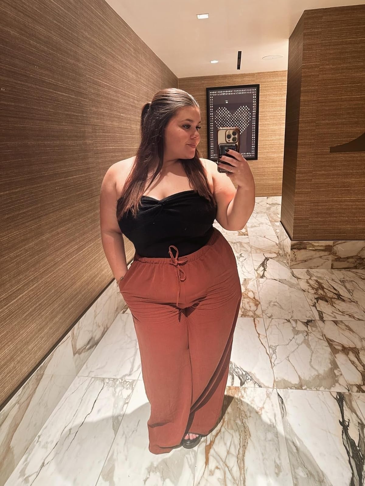 reviewer successful  a stylish strapless achromatic  apical  and high-waisted pants takes a reflector  selfie successful  a marble-floored room