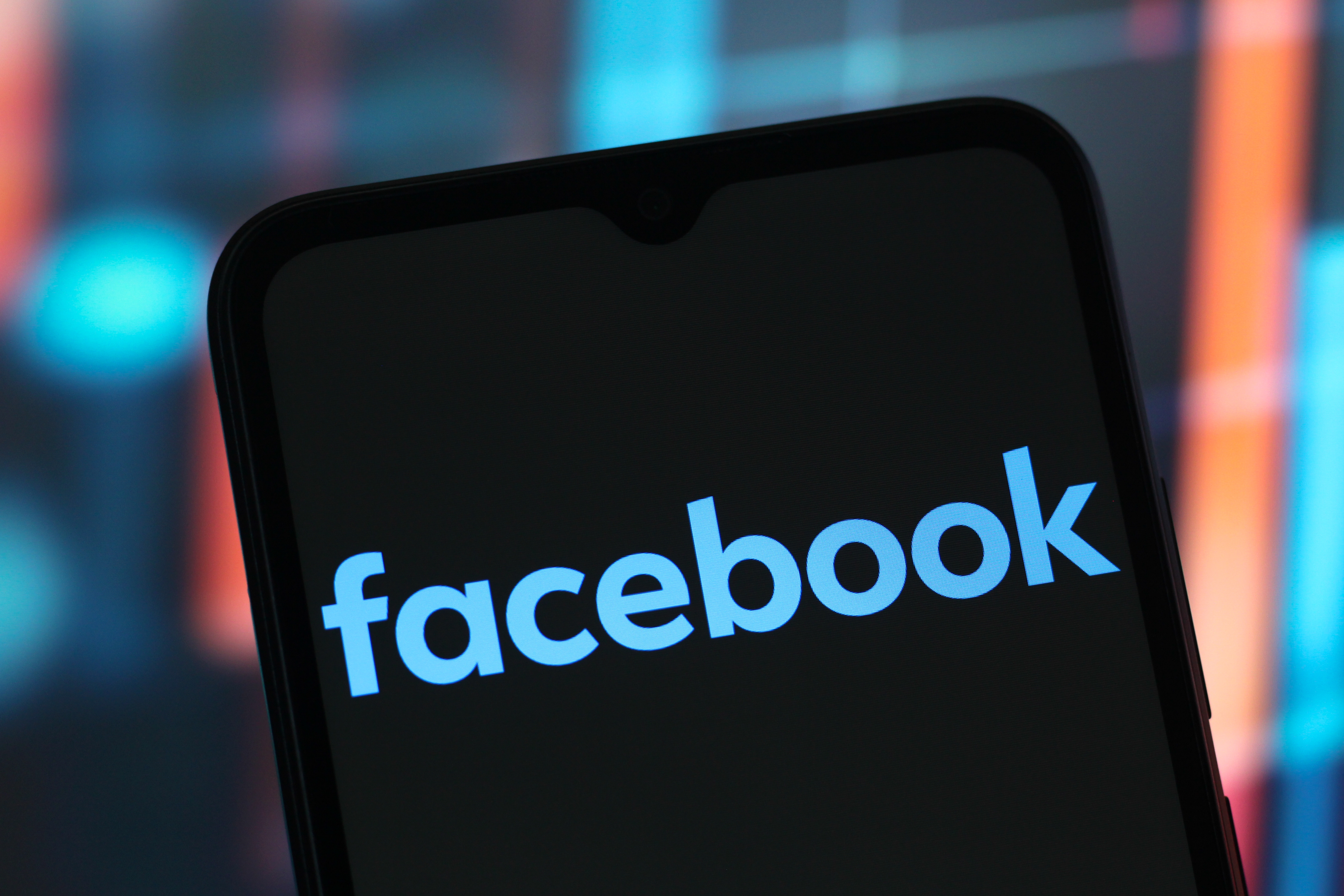 Smartphone displaying the Facebook logo on the screen against a blurred background