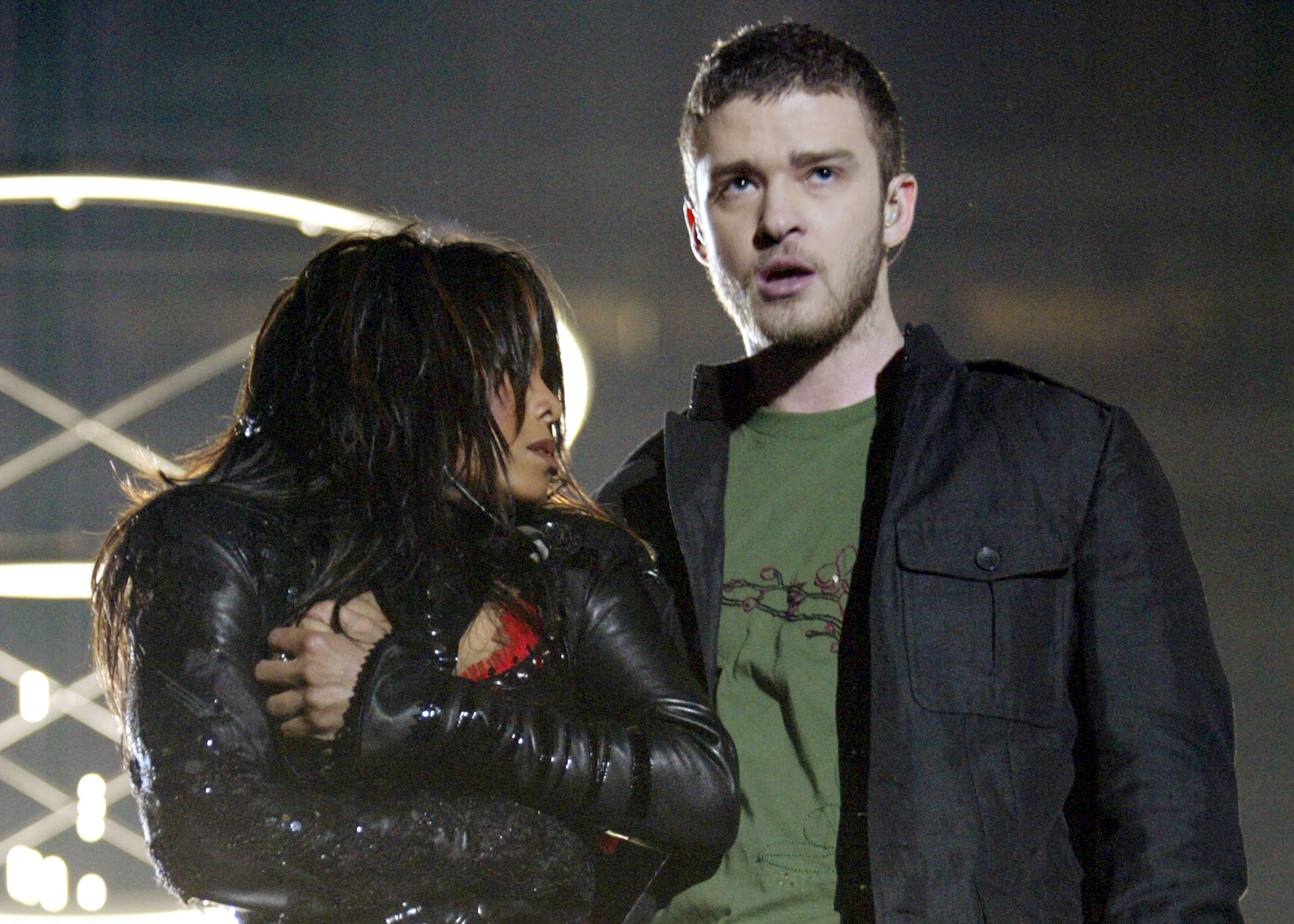 Two performers on stage; one wears a leather jacket, and the other wears a casual jacket over a t-shirt