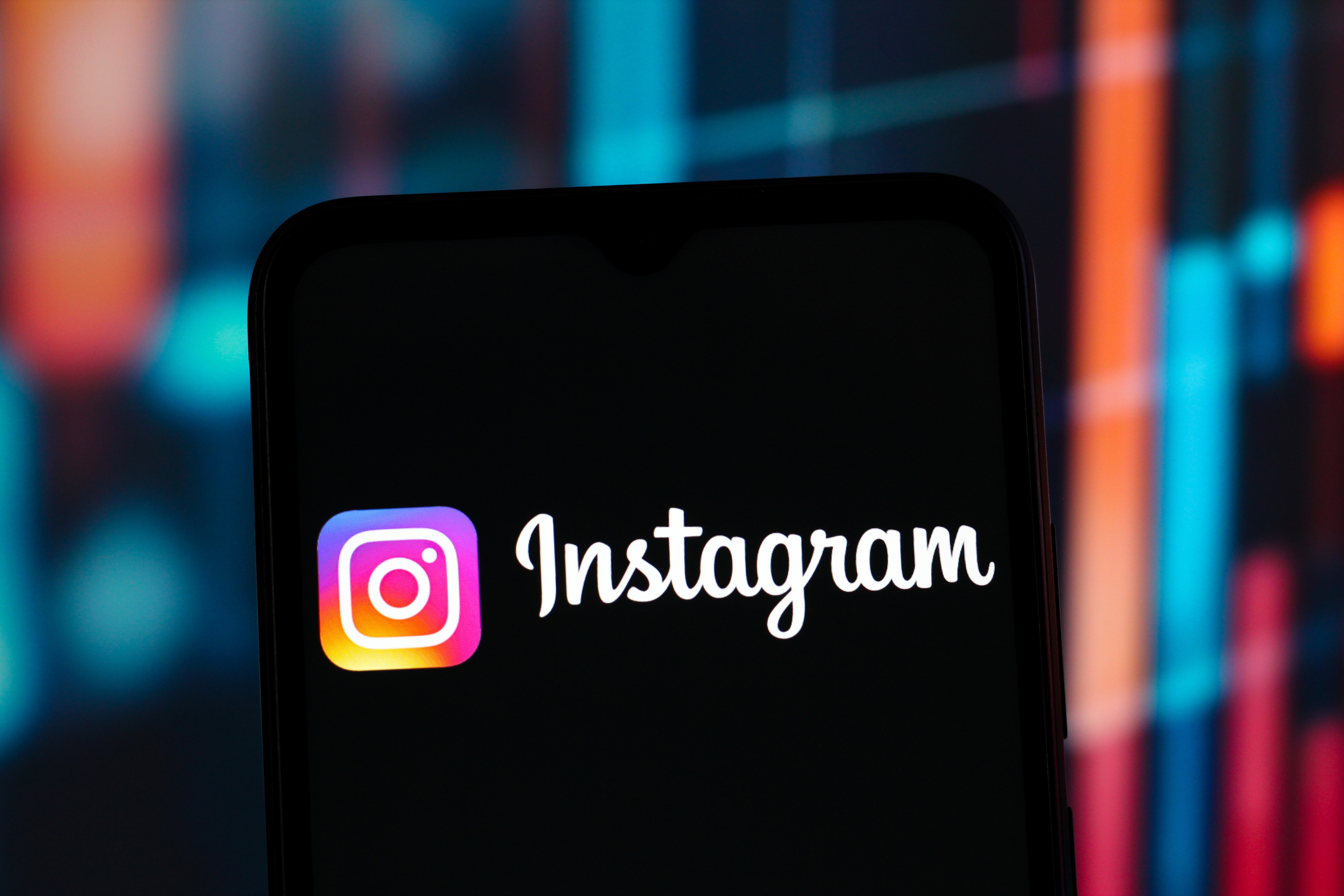 Smartphone displaying the Instagram logo and app interface, with a blurred colorful background