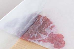 ナイフで紙の上の小さな赤い染みを切断している場面。