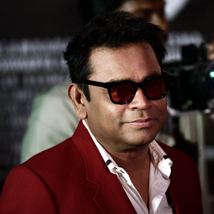 Person wearing a suit and sunglasses, standing in front of cameras at an event