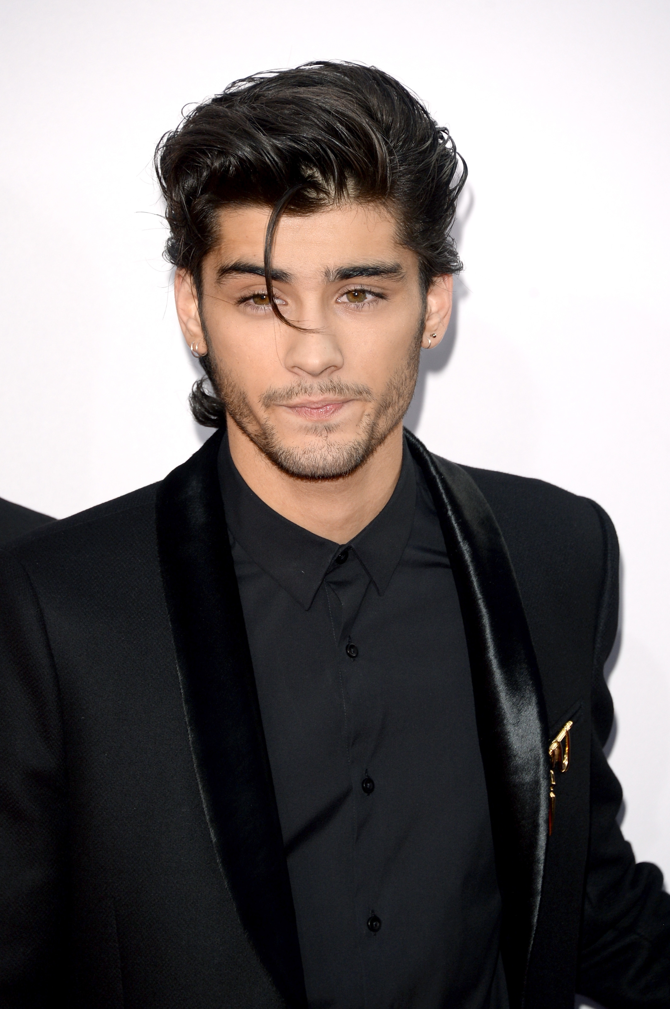 Person wearing a sleek suit with a satin lapel, looking forward with a neutral expression