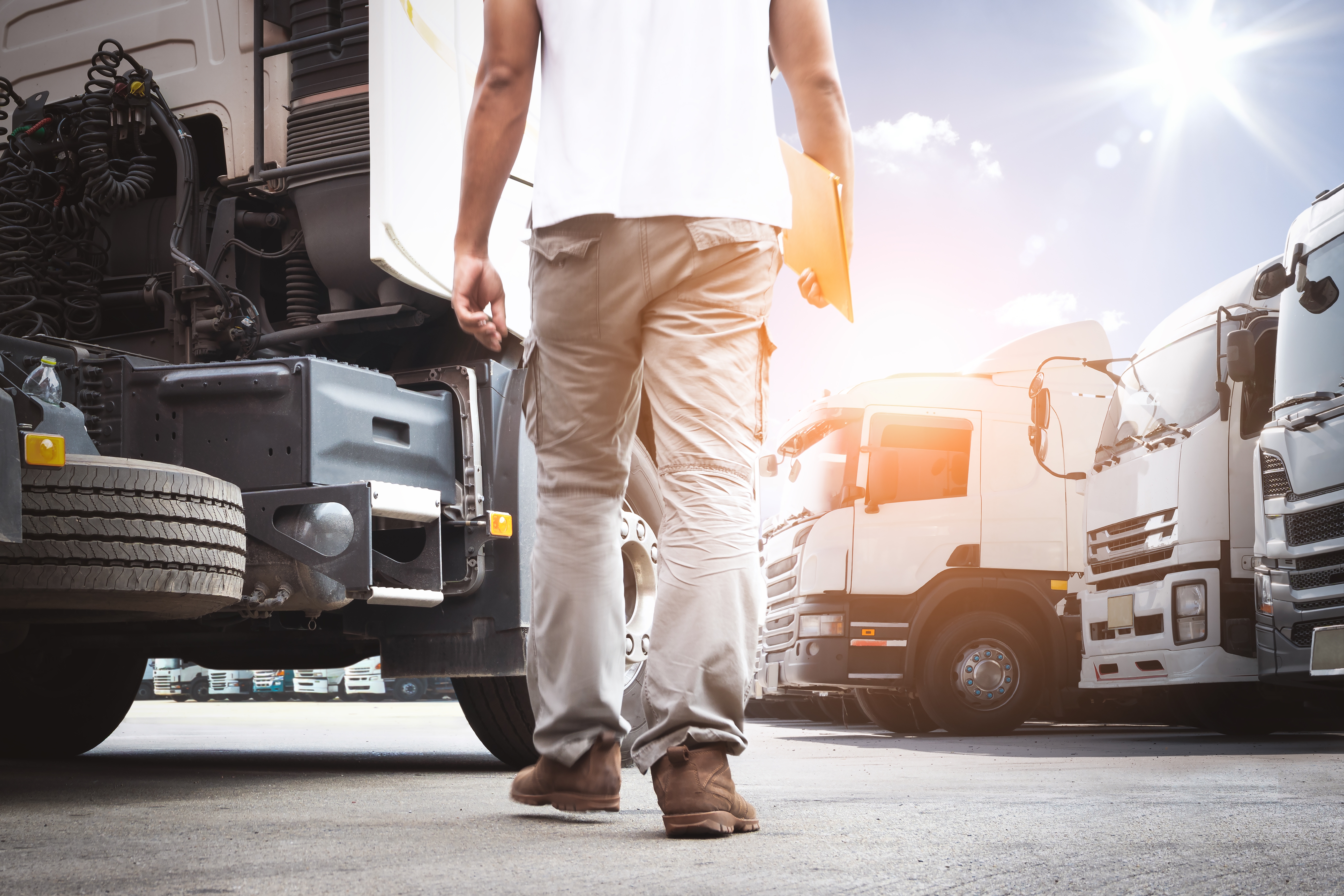 Person i tilfeldig slitasje og inspisere lastebiler på en solfylt parkeringsplass