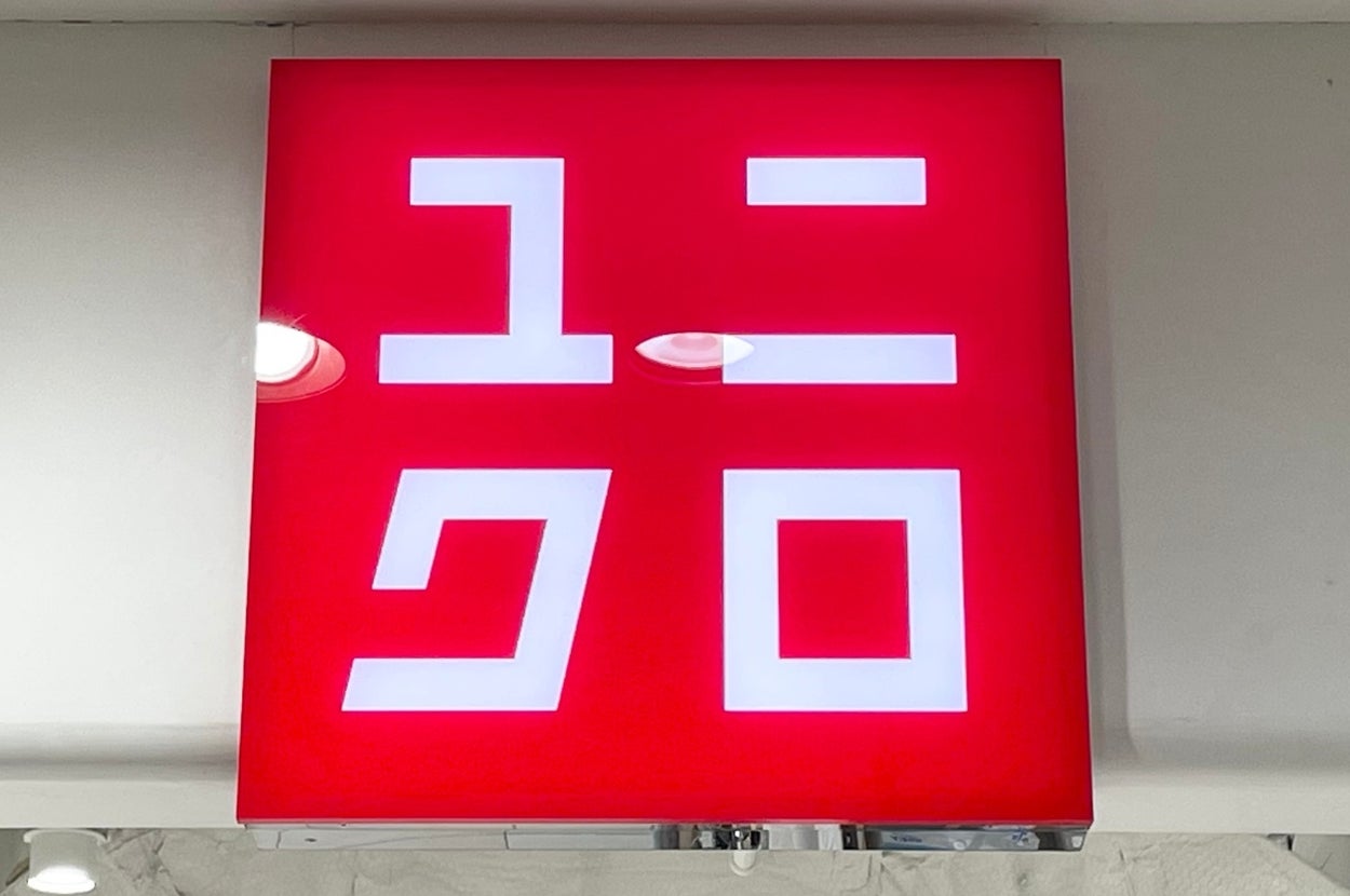 A red sign with white Japanese characters represents the Uniqlo logo, mounted indoors