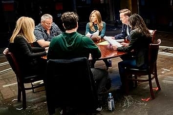 People sitting around a table engaged in a discussion, with papers on the table