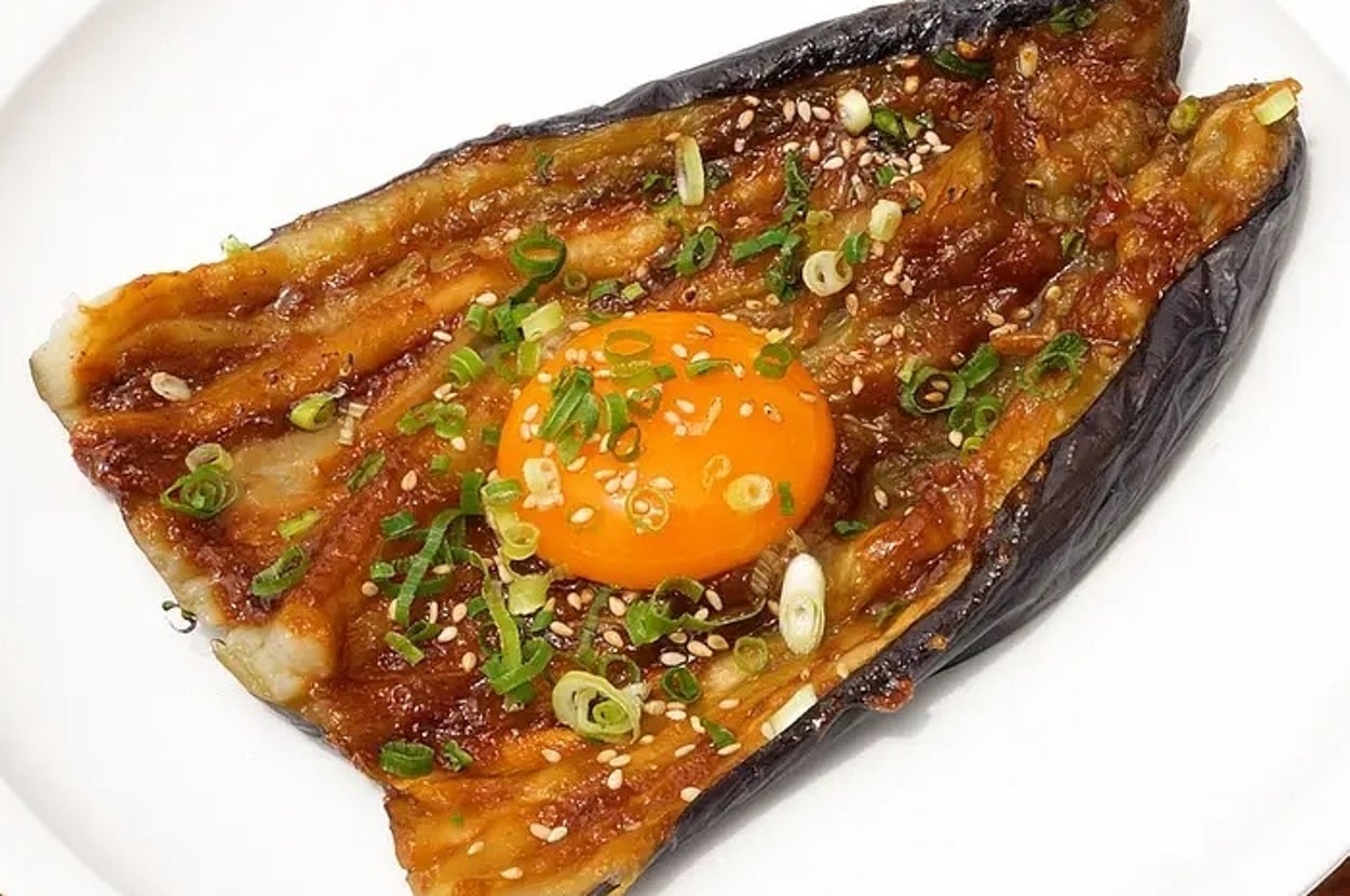 皿に盛られた焼きナスに生卵とネギのトッピング。