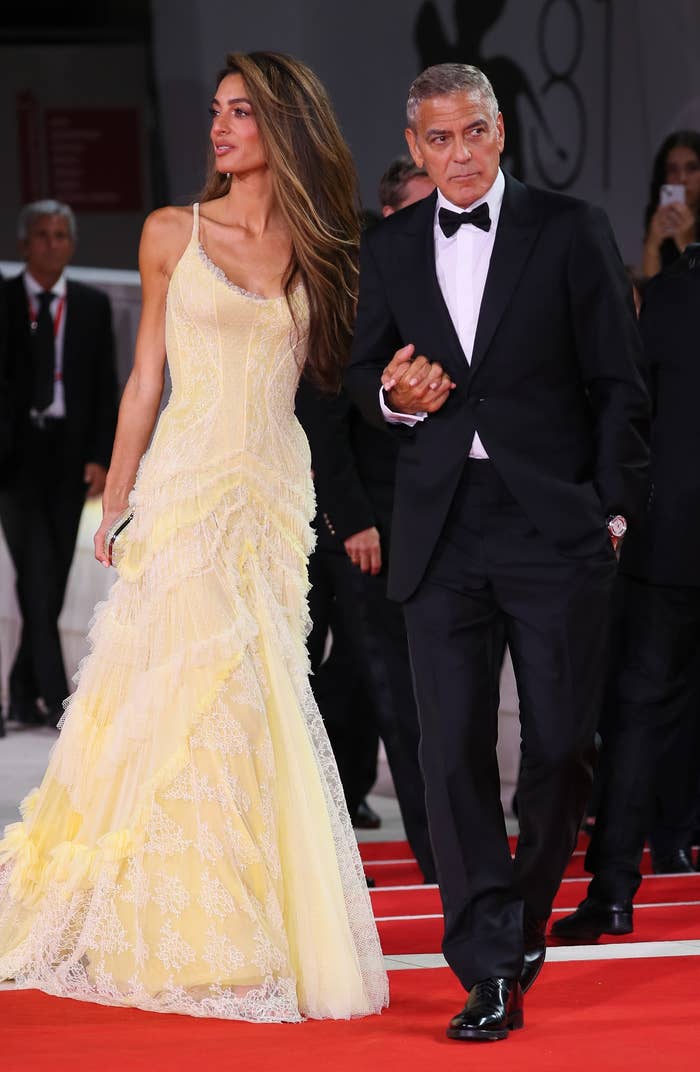 Amal Clooney and George Clooney connected a reddish carpet