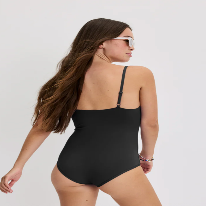 Person in a sleek one-piece swimsuit with sunglasses, posing over the shoulder