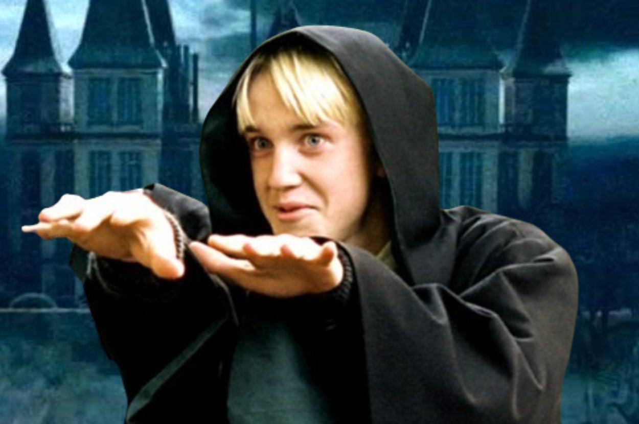 Draco in dark cloak mimics wizard casting a spell with his hands outstretched, standing in front of a gothic building background