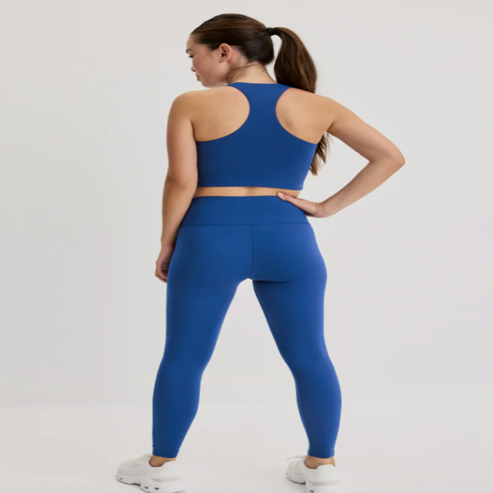 Person in matching exercise attire with racerback tank and leggings, standing with one hand on hip, suitable for activewear shopping content