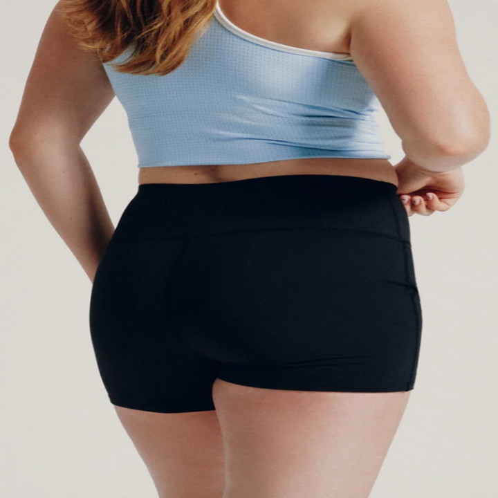 Person wearing a tank top and black high-waisted shorts, viewed from the back, showcasing activewear fit