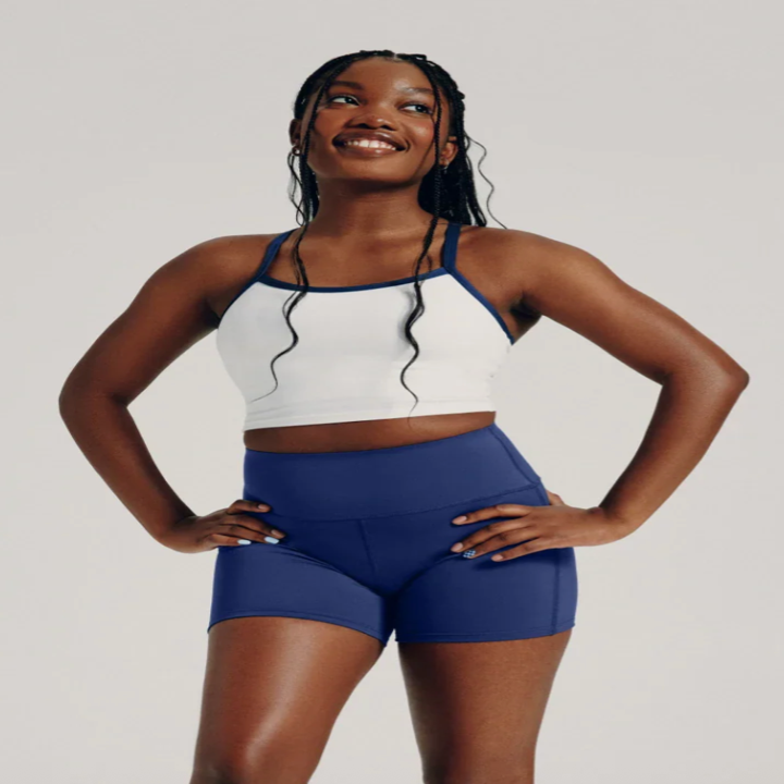 Person smiling, wearing a sporty tank top and shorts, showcasing activewear attire
