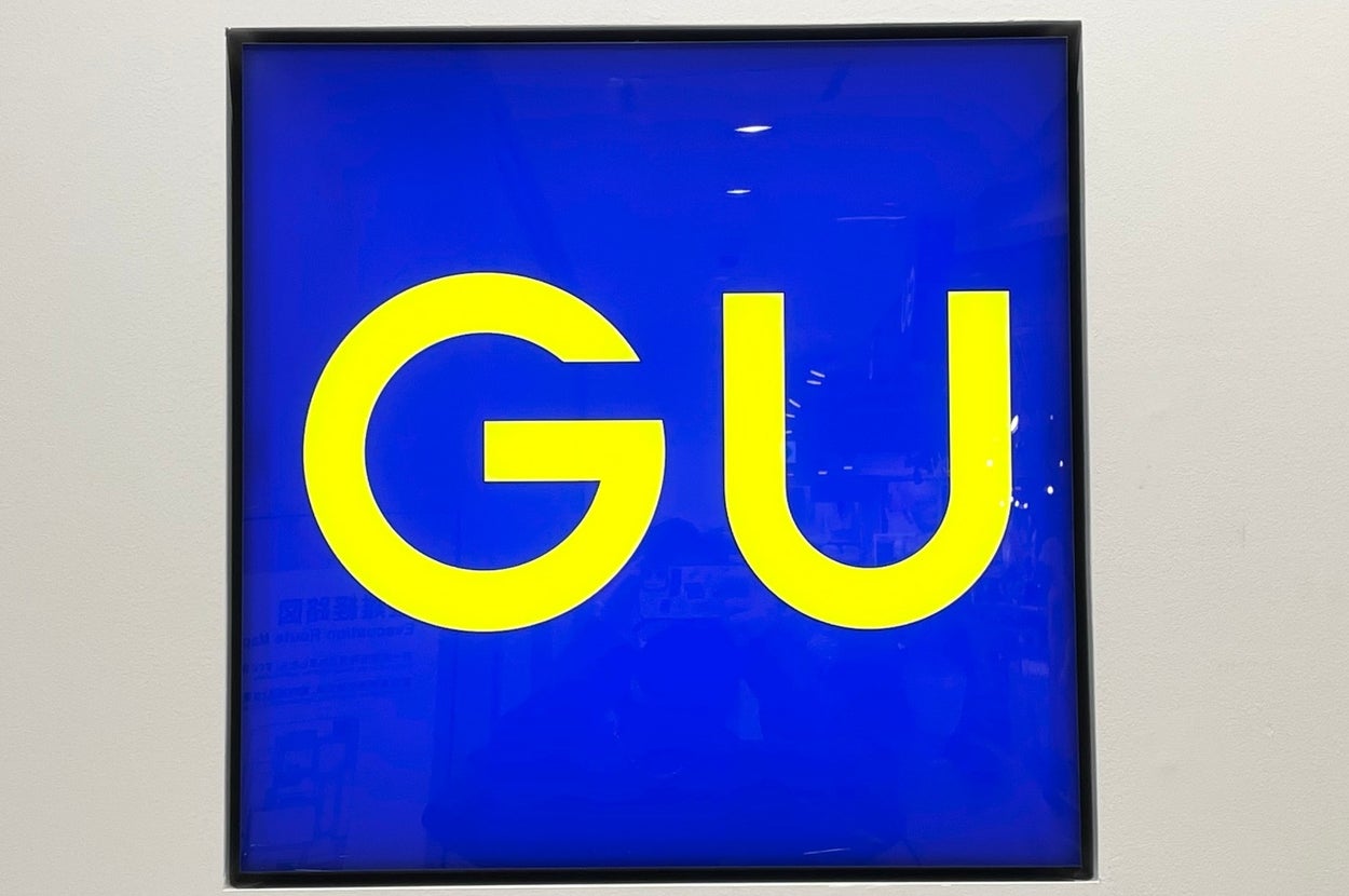 A square sign with "GU" in bold yellow letters on a dark blue background
