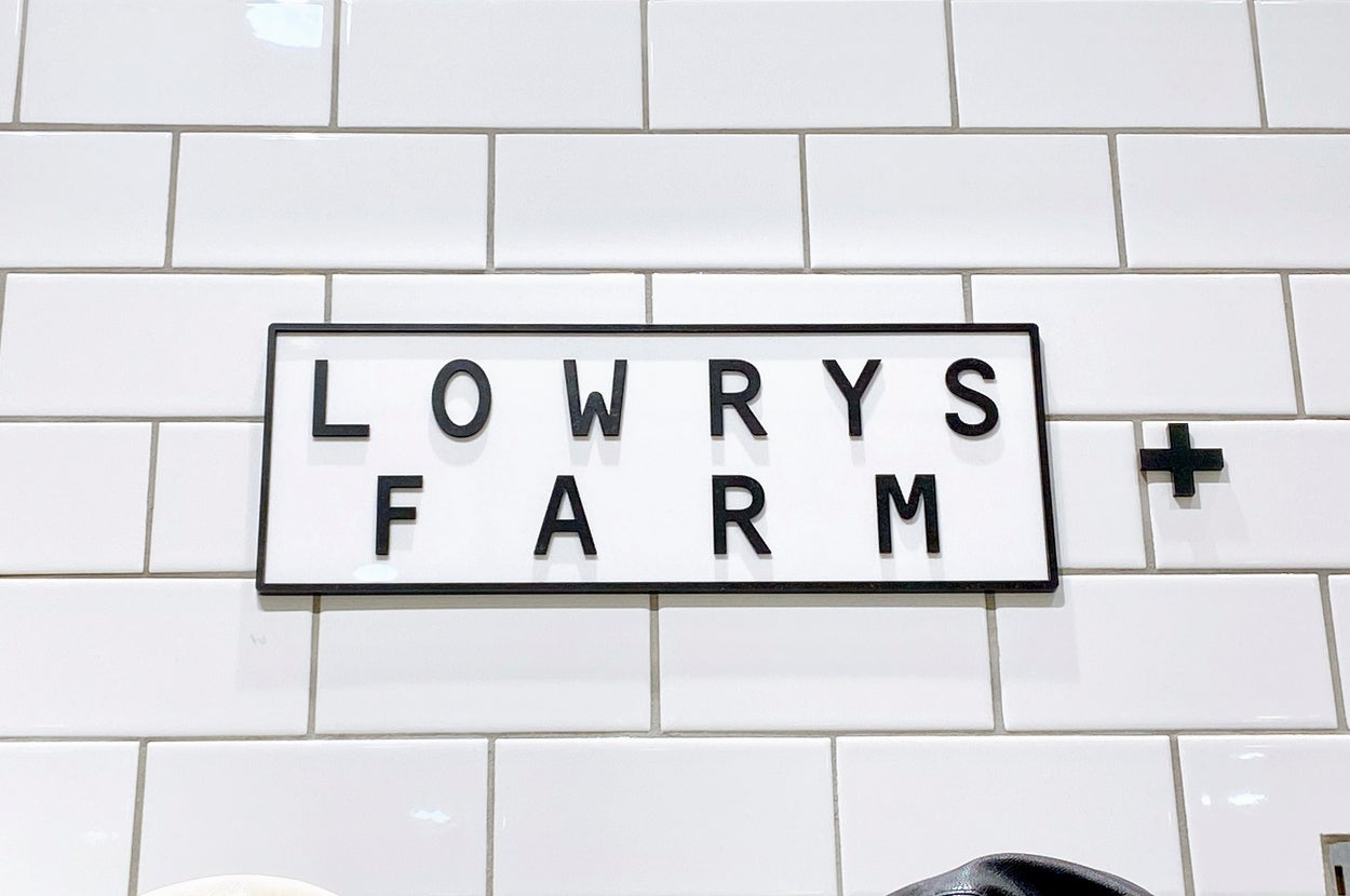 LOWRYS FARMの看板が白いタイルの壁に取り付けられている。