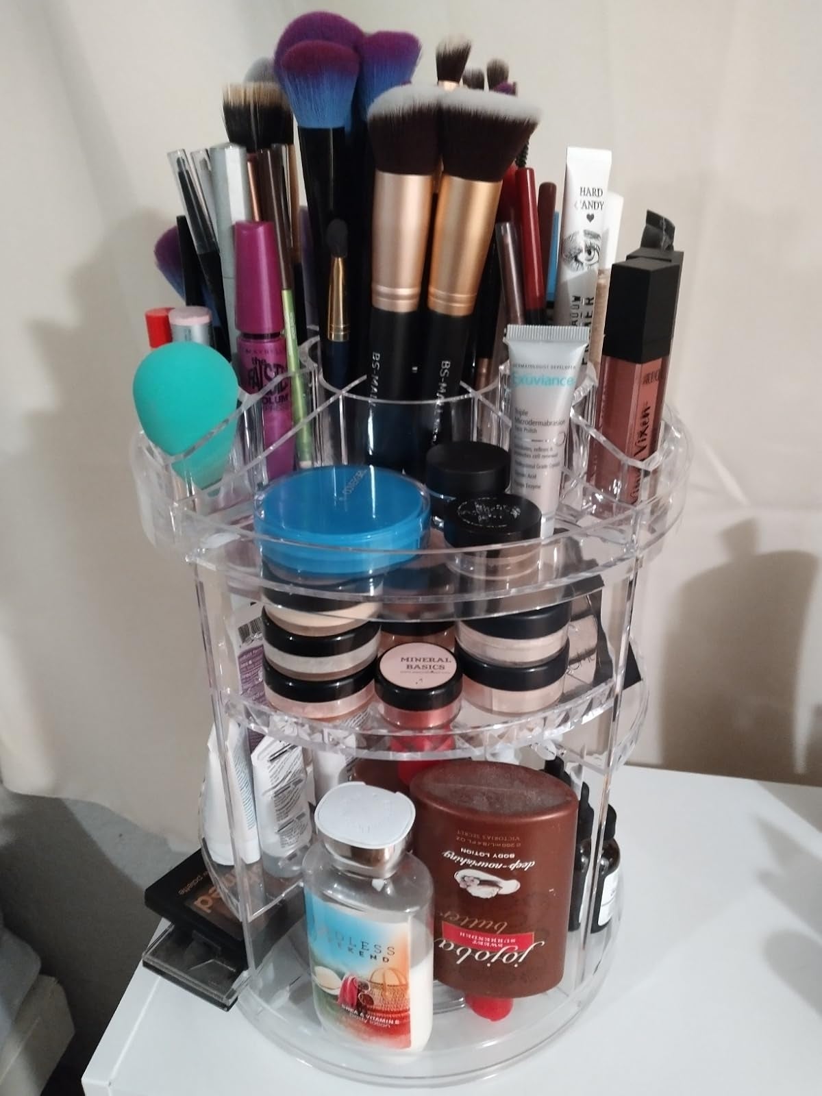 Rotating constitution  organizer filled with brushes, lipsticks, moisturizers, and different   quality   products, showcasing a assortment  of skincare and cosmetics