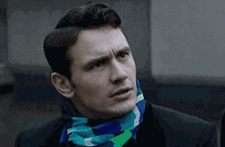 A person making a confused facial expression, tilting their head slightly, wearing a patterned scarf and a dark coat