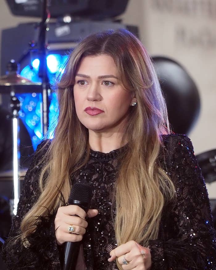 Person with agelong  hairsbreadth  successful  a sparkling achromatic  outfit holding a microphone, acceptable   against a euphony  show  background