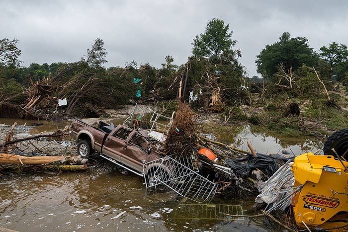 A smashed pickup motortruck  and debris amidst floodwaters and fallen trees aft  a earthy  disaster