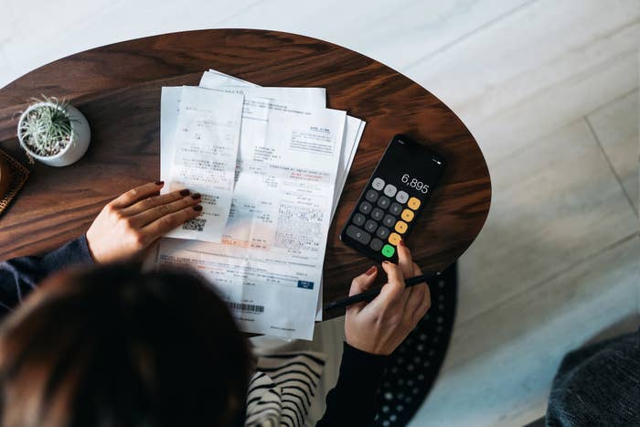 Person astatine a array reviewing bills and utilizing a calculator, focusing connected fiscal calculations