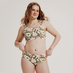 Person in floral swimwear poses confidently, showcasing a two-piece swimsuit