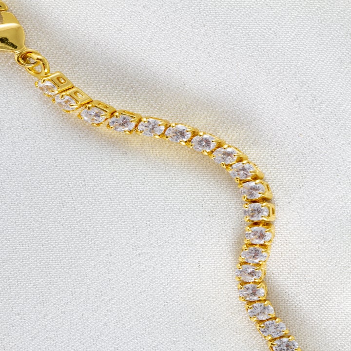 Gold chain bracelet with sparkling clear stones on a white background