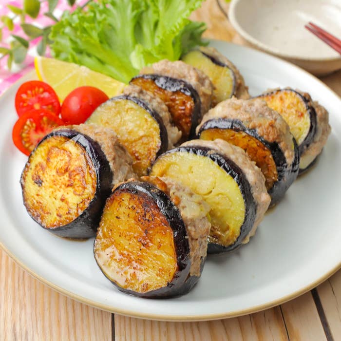 ナスと肉のスライスが交互に並べられた皿。添えられたトマトとレタスが彩りを添える。