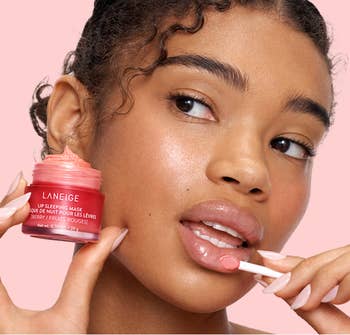A idiosyncratic applies Laneige Lip Sleeping Mask with an applicator, holding the merchandise jar. The absorption is connected articulator attraction and quality routine