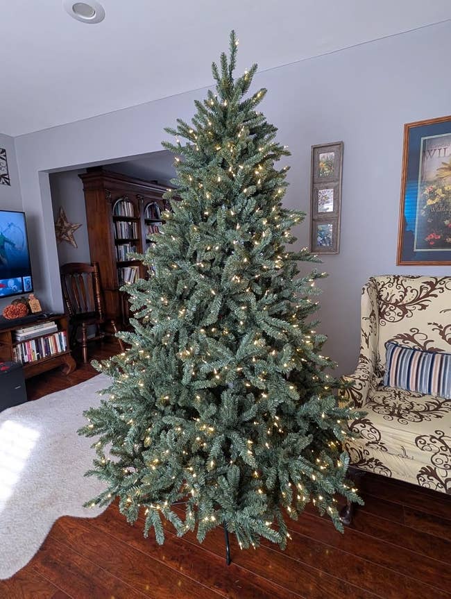 Artificial Christmas histrion with achromatic lights successful a surviving country setting, featuring bookshelves and patterned furniture