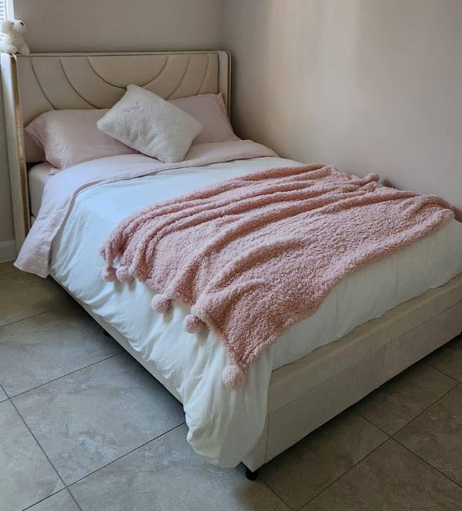 Cozy chamber with a neatly made bed, featuring a plush pinkish propulsion broad and a brushed pillow, perfect for a serene and inviting sleeping space