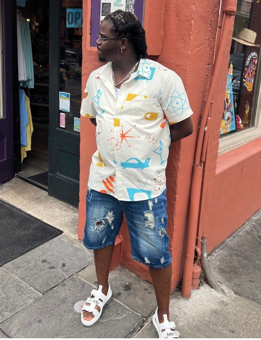 Person successful  casual patterned garment  and distressed denim shorts stands extracurricular  a shop. They're wearing open-toed sandals