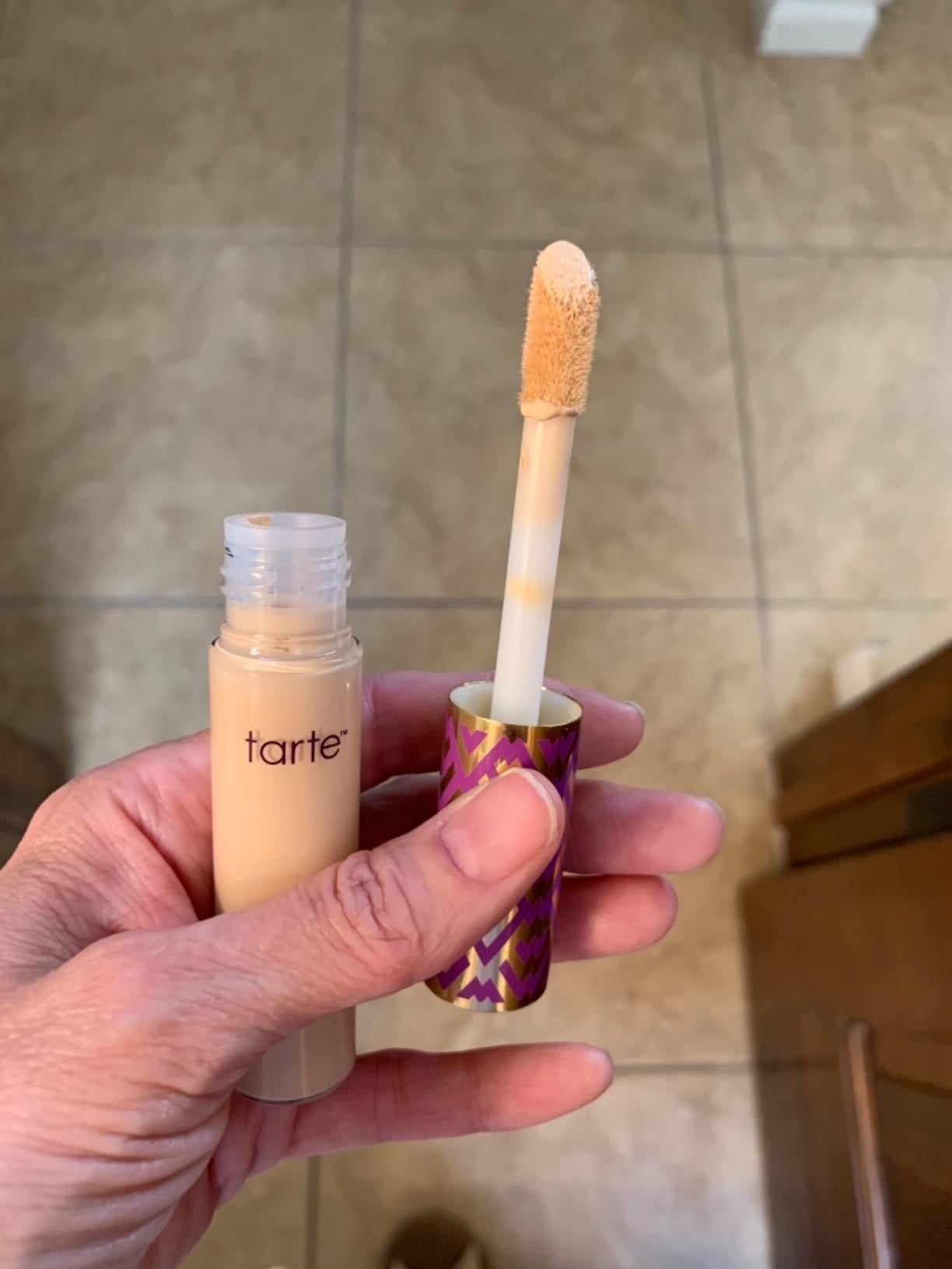 Person holding an unfastened  conduit  of Tarte concealer