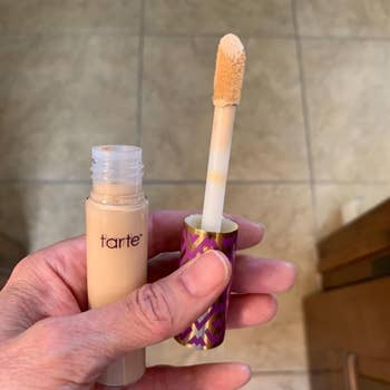 Person holding an unfastened conduit of Tarte concealer