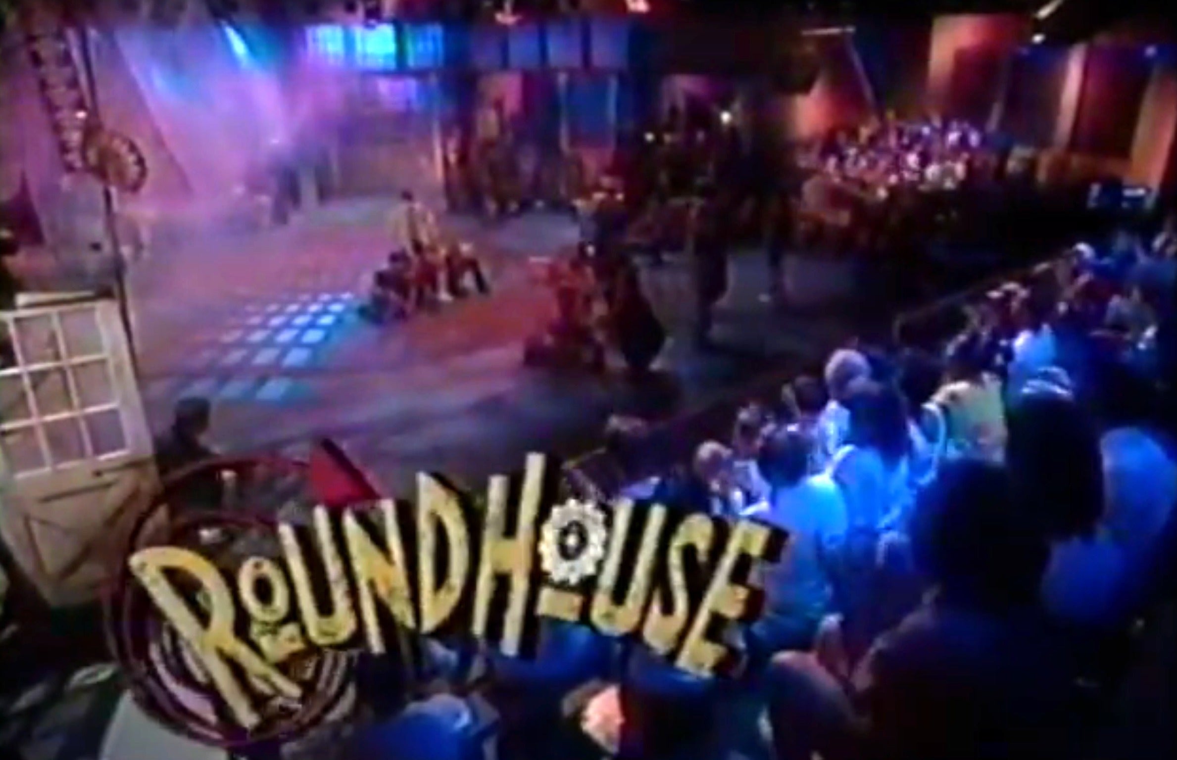 Audience watches a live performance on the set of "Roundhouse," a 90s sketch comedy TV show